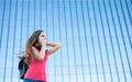 Portrait of young teenager brunette girl in coral t-shirt with long hair. girl on city talking on the smart phone. Glass building Royalty Free Stock Photo