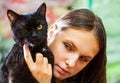 Young teenager brunette girl holding in her arms black cat. Royalty Free Stock Photo