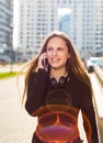 Portrait of young teenager brunette girl with long hair. girl on city in black dress talking on the smart phone in the street in a Royalty Free Stock Photo