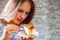 Young teenager brunette girl with long hair eating cake dessert on gray wall background Royalty Free Stock Photo