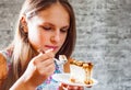 Young teenager brunette girl with long hair eating cake dessert on gray wall background Royalty Free Stock Photo