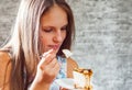 Young teenager brunette girl with long hair eating cake dessert on gray wall background Royalty Free Stock Photo