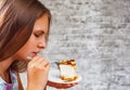 Young teenager brunette girl with long hair eating cake dessert on gray wall background Royalty Free Stock Photo