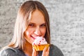 Young teenager brunette girl with long hair eating cream cake on gray wall background Royalty Free Stock Photo