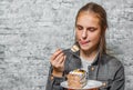 Young teenager brunette girl with long hair eating slice cake dessert on gray wall background Royalty Free Stock Photo