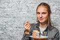 Young teenager brunette girl with long hair eating slice cake dessert on gray wall background Royalty Free Stock Photo