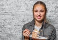 Young teenager brunette girl with long hair eating slice cake dessert on gray wall background Royalty Free Stock Photo