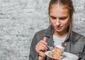 Young teenager brunette girl with long hair eating slice cake dessert on gray wall background Royalty Free Stock Photo