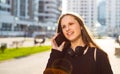 Portrait of young teenager brunette girl with long hair. girl on city in black dress talking on the smart phone in the street in a Royalty Free Stock Photo