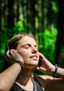 Portrait of young teenager brunette girl with long hair. Happy young woman listening to music with headphones in forest. Royalty Free Stock Photo