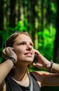 Portrait of young teenager brunette girl with long hair. Happy young woman listening to music with headphones in forest. Royalty Free Stock Photo