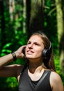 Portrait of young teenager brunette girl with long hair. Happy young woman listening to music with headphones in forest. Royalty Free Stock Photo