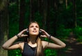 Portrait of young teenager brunette girl with long hair. Happy young woman listening to music with headphones in forest. Royalty Free Stock Photo