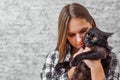 Portrait of young teenager brunette girl with long hair holding in her arms black cat on gray wall background Royalty Free Stock Photo