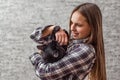 Portrait of young teenager brunette girl with long hair holding in her arms black cat on gray wall background Royalty Free Stock Photo