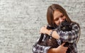 Portrait of young teenager brunette girl with long hair holding in her arms black cat on gray wall background Royalty Free Stock Photo