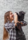 Portrait of young teenager brunette girl with long hair holding in her arms black cat on gray wall background Royalty Free Stock Photo