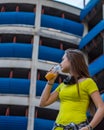 Portrait of young teenager brunette girl with long hair. Teen Girl Drinking a Bottle of fresh orange Juice on parking Background o Royalty Free Stock Photo