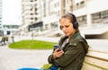 Portrait of young teenager brunette girl with long hair. young woman listening to music using mobile phone sitting on bench Royalty Free Stock Photo