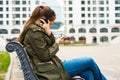 Portrait of young teenager brunette girl with long hair. young woman listening to music using mobile phone sitting on bench Royalty Free Stock Photo