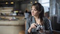 Portrait of young teenager photographer with long hair in black t-shirt in cafe. Beautiful girl holding old analog film camera in Royalty Free Stock Photo