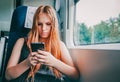 Portrait of young teenager redhead girl with long hair using smart phone while traveling Royalty Free Stock Photo