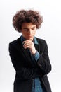 Portrait of the young thinking curly man looks down in casuals isolated on white background. Royalty Free Stock Photo