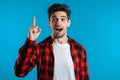 Portrait of young thinking man in red having idea moment pointing finger up Royalty Free Stock Photo