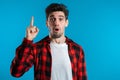 Portrait of young thinking man in red having idea moment pointing finger up Royalty Free Stock Photo