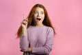 Portrait of young thinking pondering woman having idea moment pointing finger up on pink studio background. Smiling Royalty Free Stock Photo