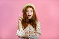 Portrait of young thinking pondering woman having idea moment pointing finger up on pink studio background. Smiling Royalty Free Stock Photo