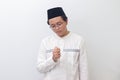 Portrait of young thoughtful Asian muslim man praying with islamic beads. Isolated image on white background Royalty Free Stock Photo