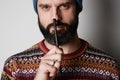 Portrait of Young thoughtful bearded man in blue beanie thinking about test over empty background.