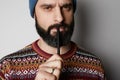 Portrait of Young thoughtful bearded man in blue beanie thinking about test over empty background.