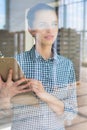 Young thoughtful farmer holding clipboard against window in greenhouse Royalty Free Stock Photo