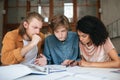 Young thoughtful people working in office. Two boys with blond hair and girl with dark curly hair sitting and studying