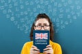 A portrait of a young thoughtful woman in glasses holding an english textbook, covering half of her face and looking up Royalty Free Stock Photo