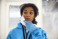 Portrait of young tired african american medical worker or nurse in protective gear taking off face mask and looking away Royalty Free Stock Photo