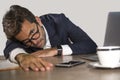 Portrait of young tired and depressed business man feeling wasted and hangover lazy working on monday at computer desk suffering Royalty Free Stock Photo