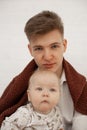 Portrait of young tired father dad covered with brown plaid holding little cute plump grey-eyed baby infant toddler. Royalty Free Stock Photo