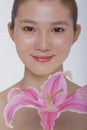 Portrait of young tranquil woman looking at camera with a large pink flower, studio shot Royalty Free Stock Photo