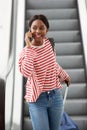 Young travel woman talking on cellphone by escalator