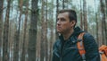 Portrait of young traveling man in woods. Close up of adult male in leather jacket with backpack in forest. Royalty Free Stock Photo