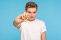 Portrait of young trendy rich man in white t-shirt holding golden bitcoin and looking at camera with clever expression