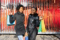 Portrait of young two african ladies friends standing over red wall and posing with shopping bags Royalty Free Stock Photo