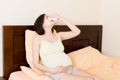 Portrait of young unhappy pregnant woman leaning on pillows on bed and blowing her nose into tissue. Future mom caught cold and Royalty Free Stock Photo