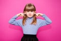 Portrait of young unhappy, stressed little girl covering her ears with fingers calling to stop noise isolated on pink Royalty Free Stock Photo