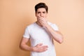 Portrait of young unsatisfied person arm on stomach covering mouth isolated on beige color background