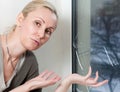 Portrait of the young upset woman of the housewife at the window which have burst from a frost with a double-glazed window