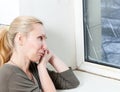 Portrait of the young upset woman of the housewife at the window which have burst from a frost window